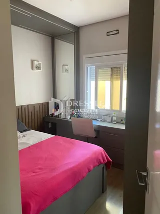 Quarto interno com cama e parede clara.