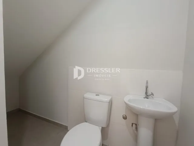 Foto de um banheiro com vaso sanitário e pia brancos.