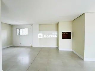 Foto de uma sala ampla e vazia com piso claro e paredes brancas.