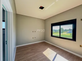 Sala de estar com piso de madeira e grande janela com vista para a natureza.