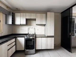 Foto de uma cozinha moderna com armários brancos e bancadas escuras.