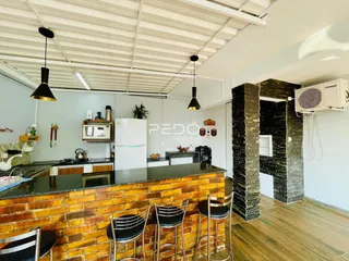 Cozinha e área de jantar com piso de madeira e parede de tijolos expostos em uma residência.