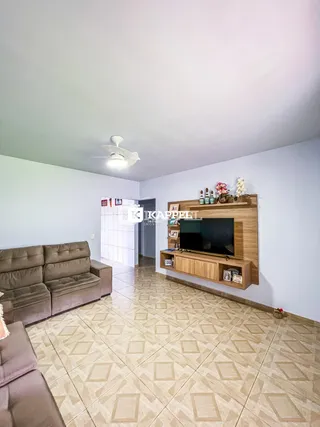 Sala de estar com sofá marrom e painel de TV de madeira.