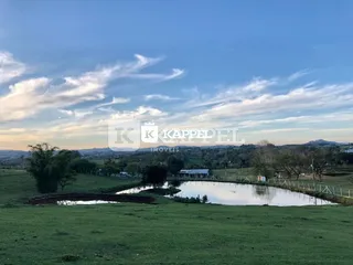 Vista panorâmica de uma área verde com um corpo d'água em um terreno no Brasil.