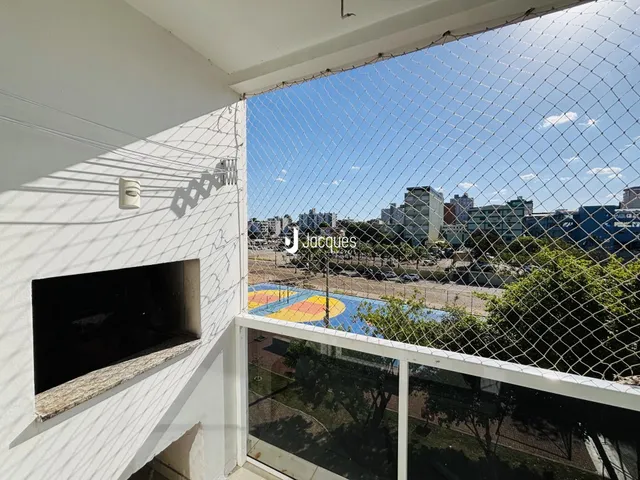 Vista externa de uma propriedade com cerca de arame e paisagem urbana ao fundo.
