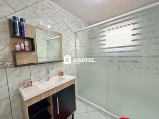 Banheiro com bancada branca e box de vidro transparente.