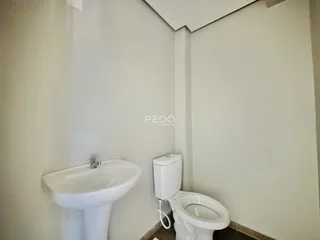 Foto de um banheiro interno com pia e vaso sanitário brancos.