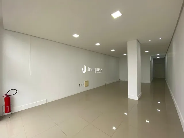 Corredor interno de uma residência com paredes brancas e piso claro.