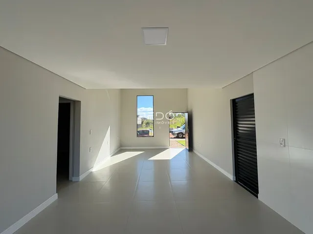 Vista de um corredor interno com paredes brancas e piso claro.
