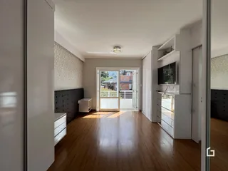 Uma sala de estar com piso de madeira e portas de vidro que dão acesso ao exterior.