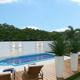 Foto da piscina externa com deck de madeira e vegetação ao fundo.