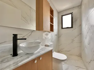 Banheiro moderno com revestimento em mármore nas paredes e piso.
