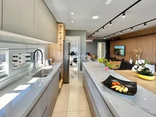 Vista da cozinha moderna com armários brancos e bancada clara.