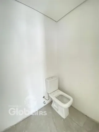 Vista interna de um banheiro com azulejos brancos.
