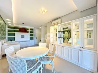 Sala de estar e jantar com armários brancos em um apartamento.