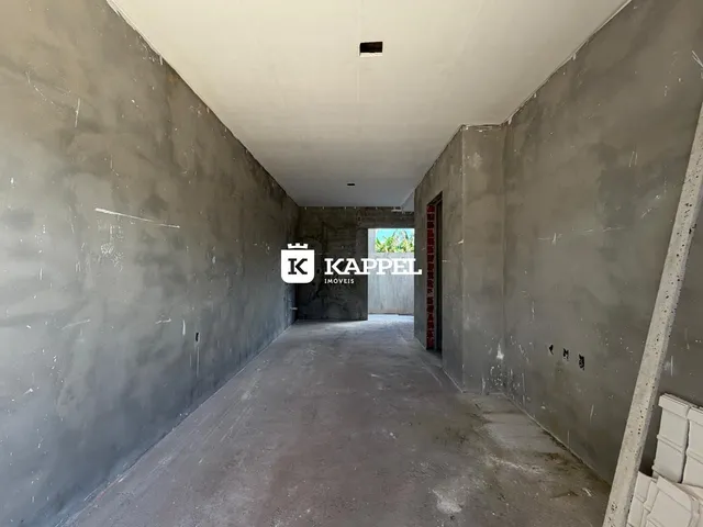 Corredor interno com paredes de concreto aparente e piso cru.