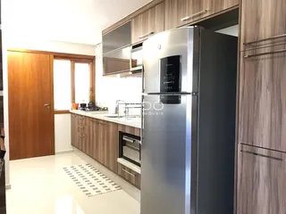Vista interna de uma cozinha moderna com armários de madeira e eletrodomésticos de aço inoxidável.