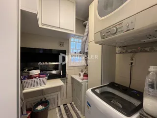 Vista interna de uma cozinha com armários brancos e eletrodomésticos escuros.