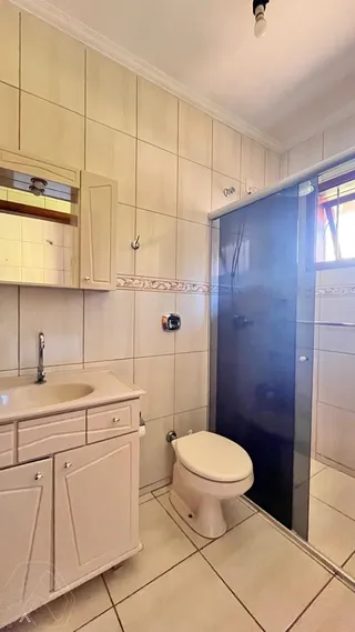 Banheiro com revestimento de azulejos brancos e bancada de mármore.