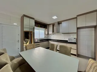 Sala de estar com cozinha integrada e mesa de jantar em um imóvel no Brasil.