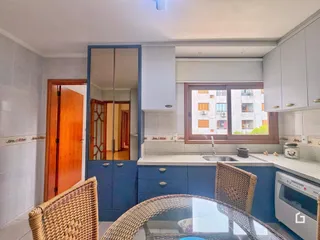 Interior da cozinha com armários azuis e janela de madeira.