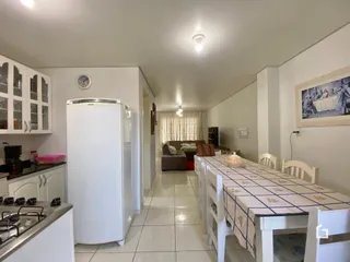 Vista interna de uma cozinha com armários brancos e piso cerâmico.