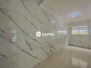 Vista de um corredor com revestimento de mármore branco nas paredes.