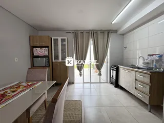 Foto de um ambiente interno com mesa de jantar e área de cozinha em um apartamento.