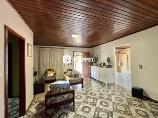 Sala de estar com piso de cerâmica e teto de madeira aparente.
