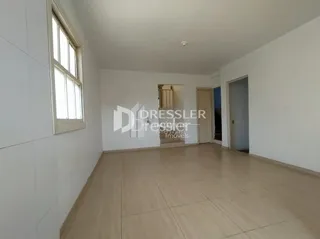 Vista interna de um ambiente com piso de madeira clara e paredes brancas.