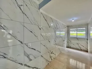 Parede interna com revestimento de mármore branco em um corredor.