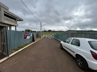 Vista externa de uma propriedade com cerca de metal e estrada de acesso.
