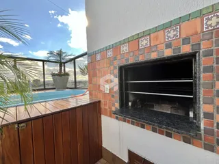 Vista da área externa com piscina e parede de tijolos no imóvel.