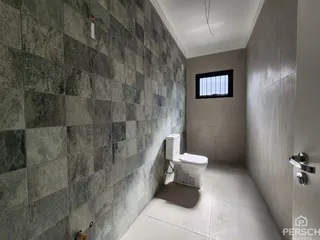 Banheiro com revestimento de azulejos cinzas e vaso sanitário branco.