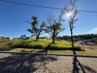 Vista externa de uma propriedade com árvores e gramado sob luz solar.