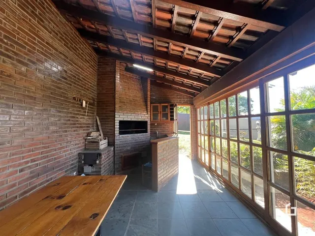 Interior de uma sala com paredes de tijolo aparente e grandes janelas.