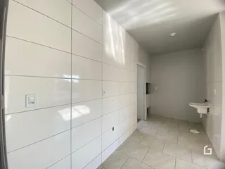 Corredor interno com revestimento de cerâmica branca.