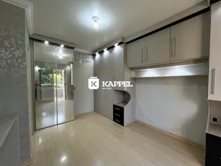 Cozinha moderna com armários em tons neutros e piso de madeira clara.