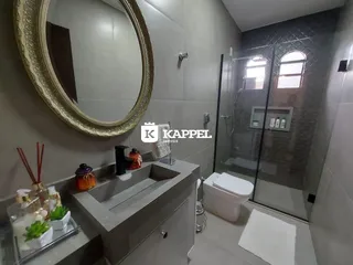 Banheiro com bancada e box de vidro transparente.