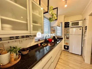 Cozinha com armários brancos e bancadas escuras em um ambiente bem iluminado.
