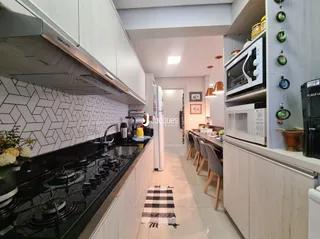 Cozinha moderna com armários brancos e bancadas escuras.