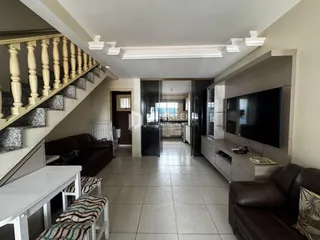 Foto de uma sala de estar com escadaria e sofá de couro marrom.