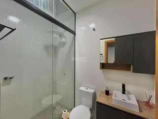 Foto de um banheiro com box de vidro e louças brancas.