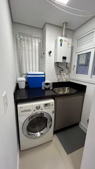 Foto de uma área de serviço com máquina de lavar e pia.