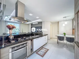 Cozinha moderna com bancada escura e armários brancos em um apartamento.