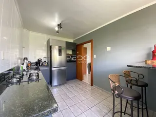 Uma cozinha com armários e piso cerâmico em um imóvel no Brasil.