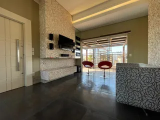 Sala de estar ampla com sofá e televisão em um ambiente moderno com vista para o exterior.