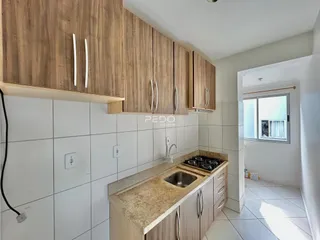 Cozinha com armários de madeira e revestimento branco na residência.