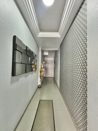 Corredor interno de um imóvel com paredes texturizadas e piso claro.