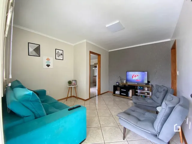 Sala de estar com sofá azul e poltronas cinzas em um apartamento.
